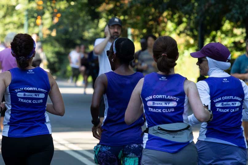 4 women in purple shirts running away from the camera